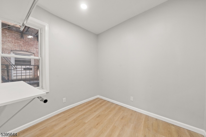 57 Henry Street, Unit A1 Passaic, NJ 07055 - Photo 10 of 14 a view of empty room with wooden floor and fan