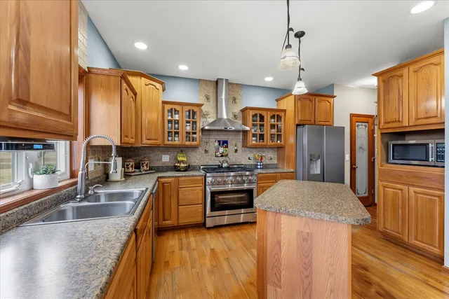 a kitchen with stainless steel appliances granite countertop a refrigerator a stove top oven a sink and dishwasher