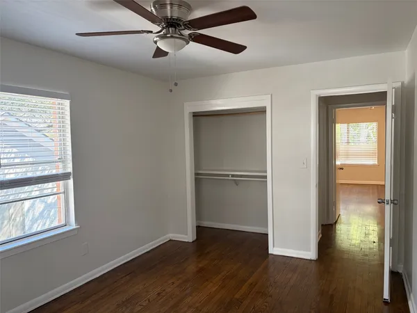 an empty room with wooden floor closet and windows