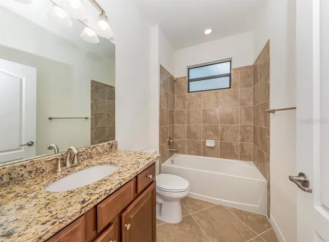a bathroom with a granite countertop sink a toilet and bathtub