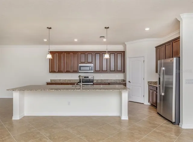 a kitchen with stainless steel appliances granite countertop a sink refrigerator and cabinets