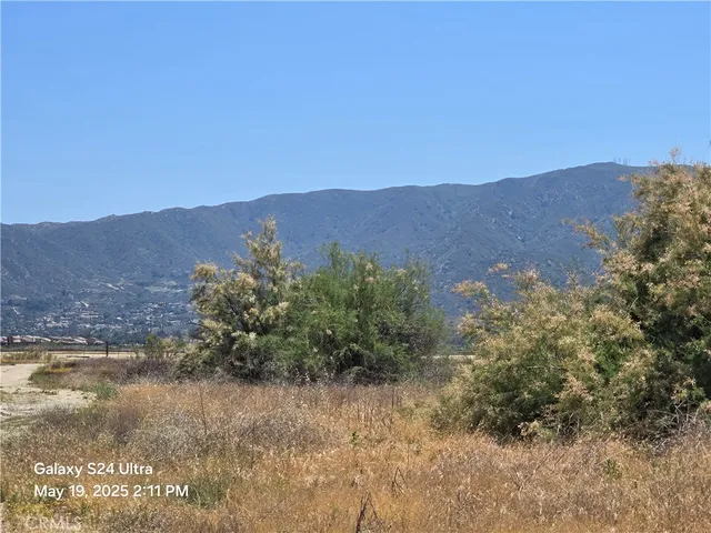 a view of a lush green field with mountains in the background