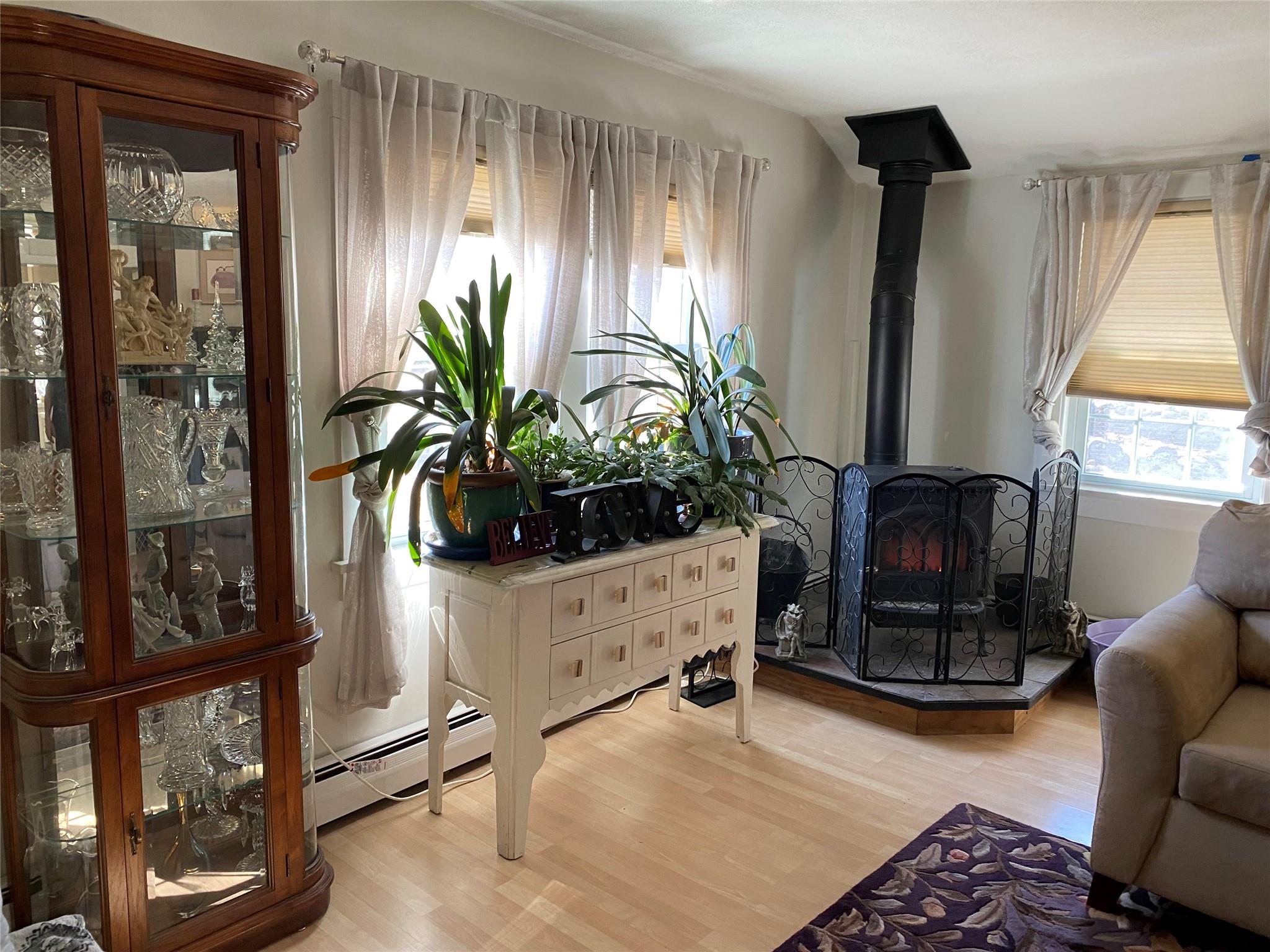 168 Prospect Road Monroe, NY 10950 - Photo 5 of 15 Sitting room featuring baseboard heating, light wood-style flooring, and a wood stove