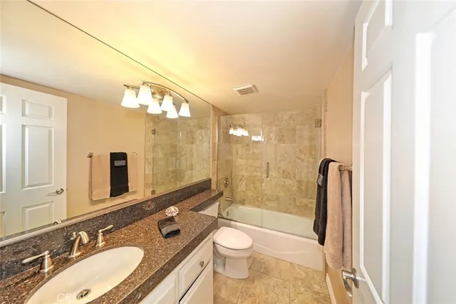 a bathroom with a granite countertop sink toilet a mirror and shower