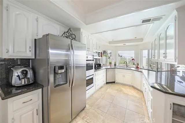 a large kitchen with stainless steel appliances kitchen island granite countertop a refrigerator and a sink