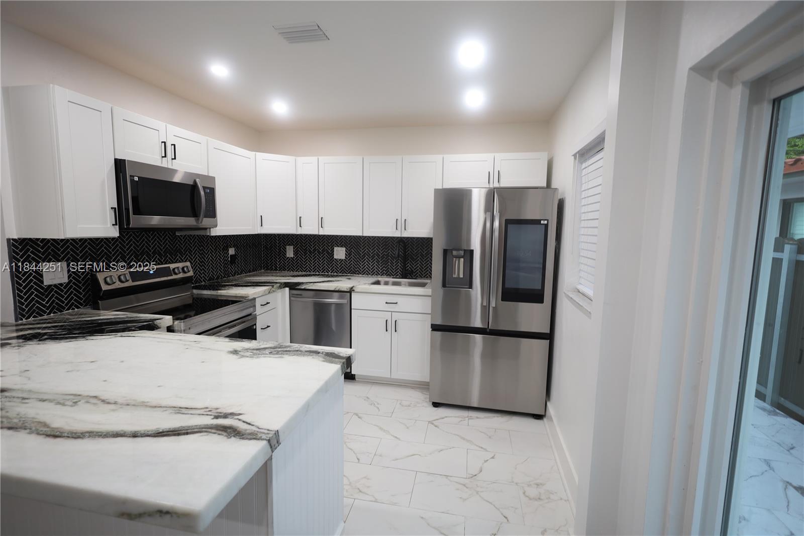 3955 Southwest 69th Avenue Miami, FL 33155 - Photo 10 of 35 a kitchen with white cabinets and stainless steel appliances