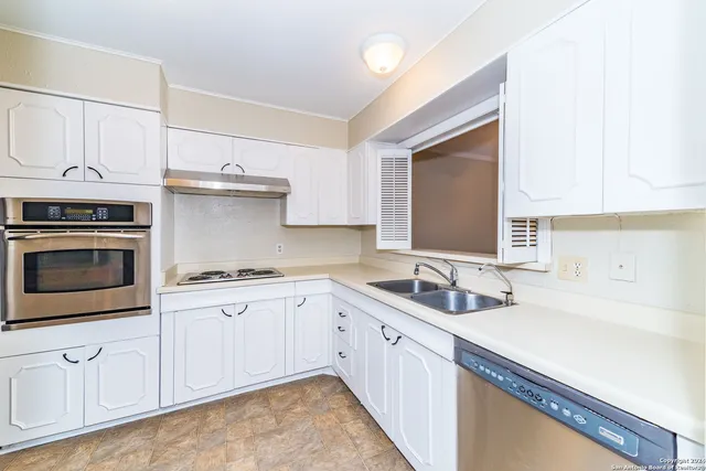a kitchen with granite countertop a sink stainless steel appliances and cabinets