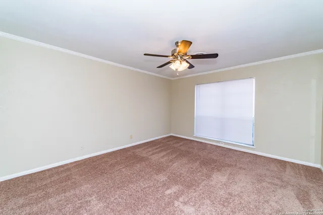 a view of a big room with windows and a ceiling fan