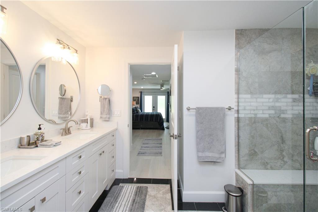 1555 Crayton Road Naples, FL 34102 - Photo 19 of 50 Bathroom with french doors, vanity, tile patterned floors, and a shower with door