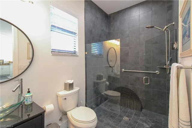 a white toilet sitting next to a bathroom sink and a mirror