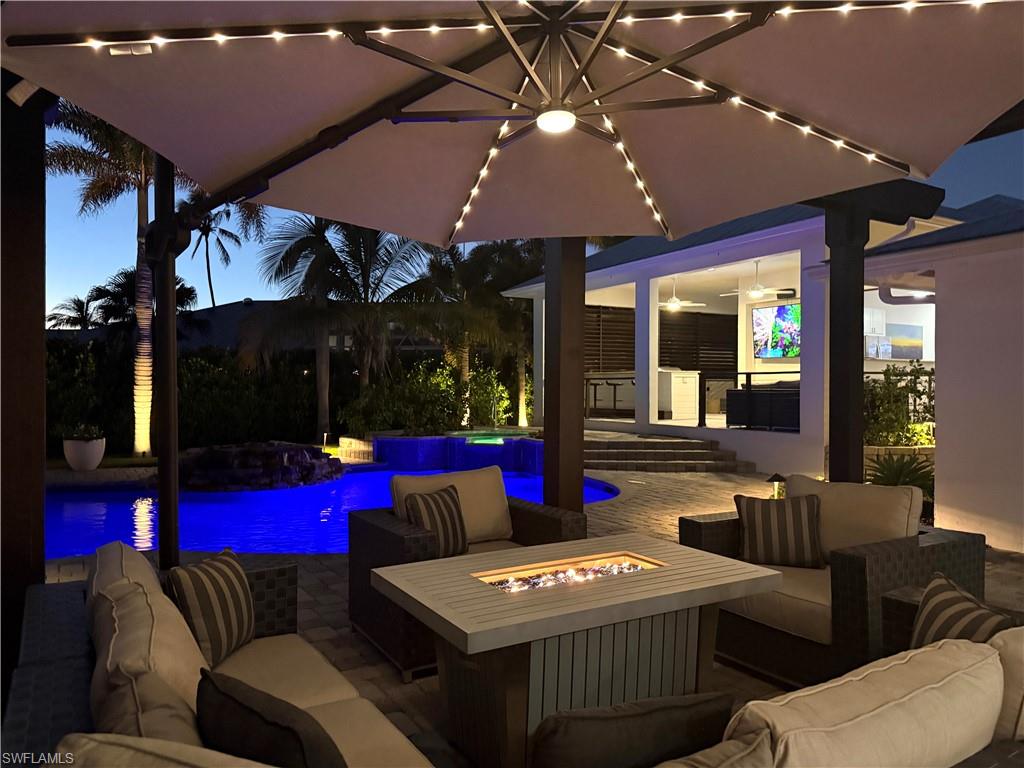 1555 Crayton Road Naples, FL 34102 - Photo 46 of 50 Patio terrace at dusk with ceiling fan and an outdoor living space with a fire pit