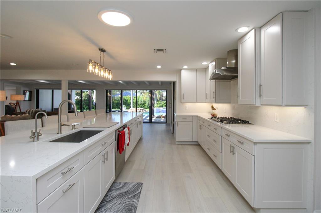 1555 Crayton Road Naples, FL 34102 - Photo 9 of 50 Kitchen featuring white cabinets, pendant lighting, sink, and wall chimney range hood