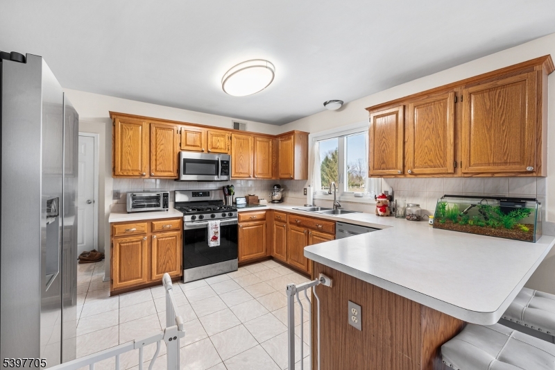 50 Blau Road Hackettstown, NJ 07840 - Photo 14 of 35 a kitchen with stainless steel appliances granite countertop a stove top oven a sink dishwasher a dining table and chairs with wooden floor