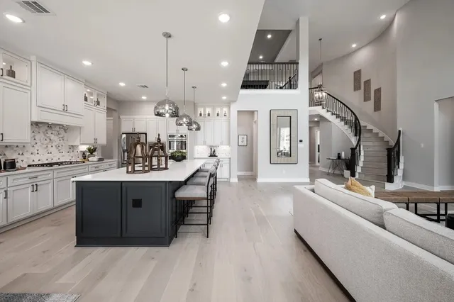 a large white kitchen with a large island oven a sink stainless steel appliances and cabinets