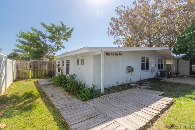 a backyard of a house with plants and trees with wooden fence