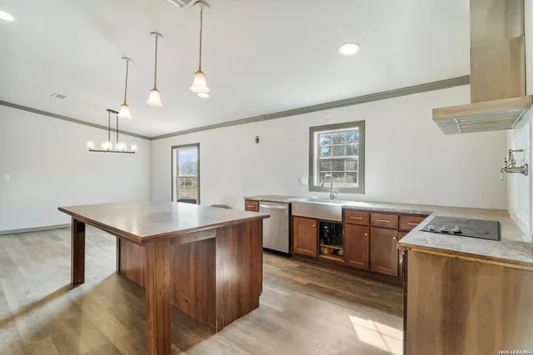 a kitchen with kitchen island granite countertop a sink a counter space appliances and cabinets