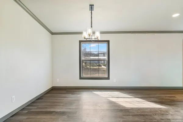 an empty room with wooden floor chandelier and windows
