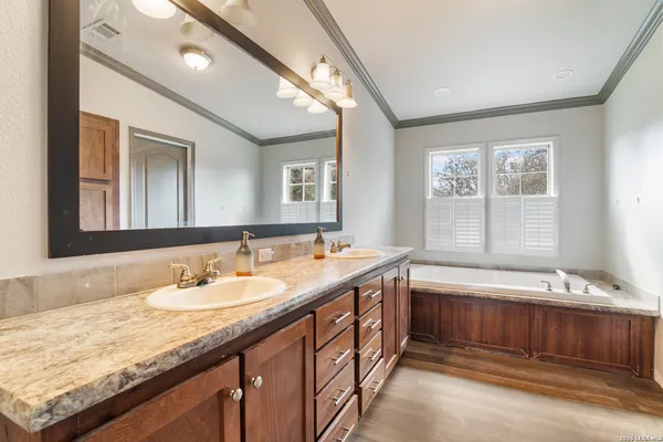 a bathroom with a granite countertop double vanity sink and a bathtub