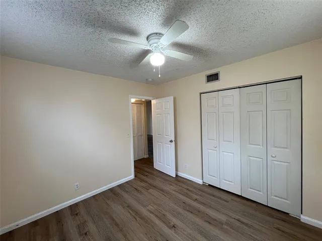 an empty room with wooden floor fan and windows