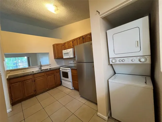 a kitchen with granite countertop a refrigerator and a stove top oven