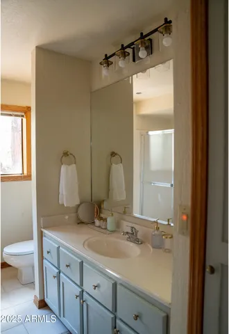 a bathroom with a double vanity sink and mirror with toilet