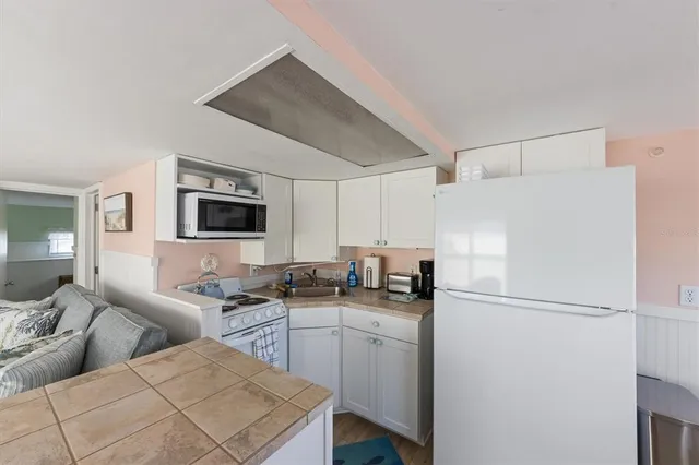 a kitchen with stainless steel appliances a refrigerator a stove a microwave a sink and white cabinets