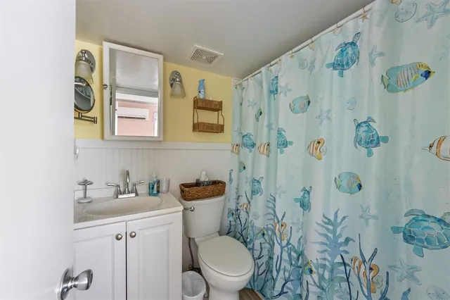 a bathroom with a toilet sink and shower curtain