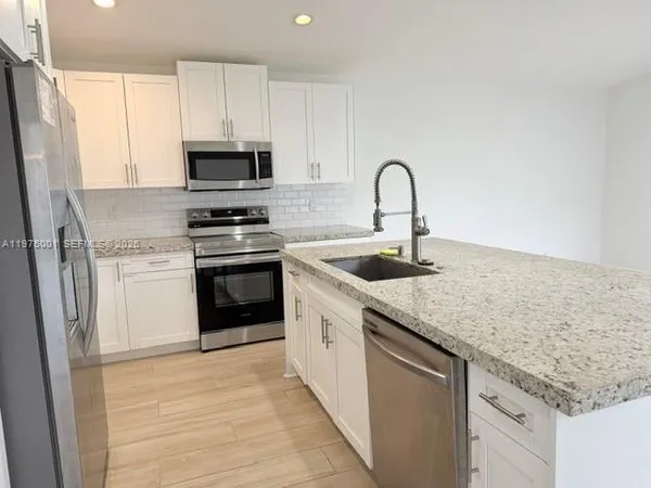 a kitchen with granite countertop white cabinets and white appliances