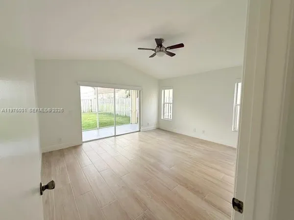 a view of an empty room with a window and wooden floor