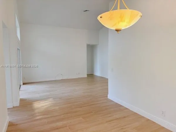 an empty room with a lamp and wooden floor