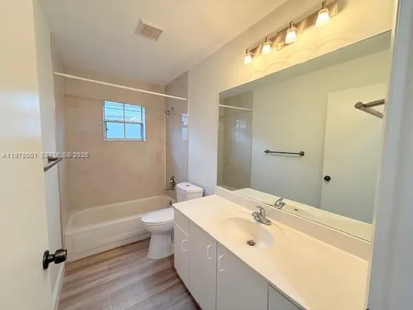 a bathroom with a bathtub shower sink vanity and toilet