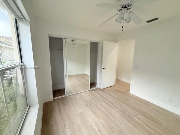 a view of empty room with wooden floor and fan