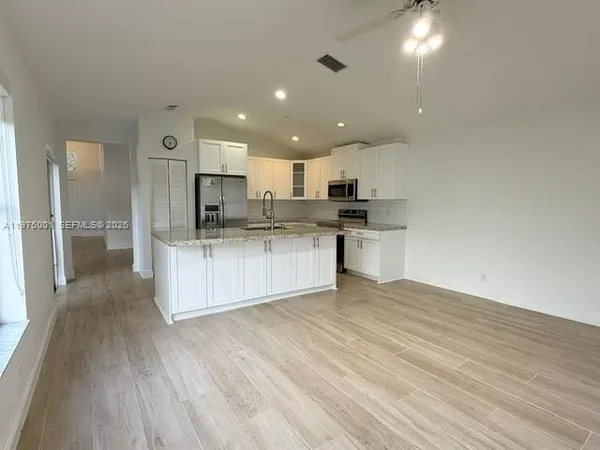 a view of kitchen with kitchen island wooden floor center island and stainless steel appliances