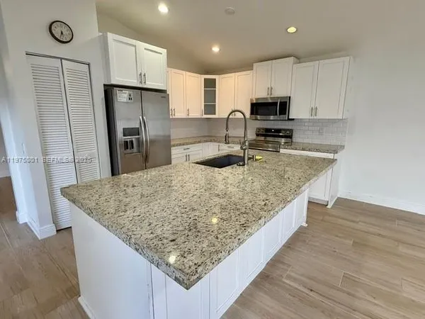 a kitchen with stainless steel appliances granite countertop a sink refrigerator and microwave