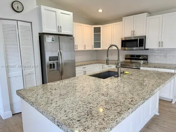 a kitchen with stainless steel appliances granite countertop a sink stove microwave and refrigerator