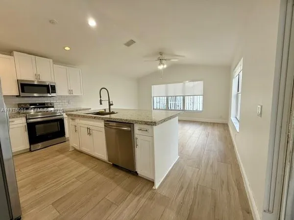 a kitchen with granite countertop a sink and steel appliances
