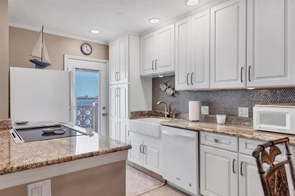 a kitchen with granite countertop a sink stove and refrigerator