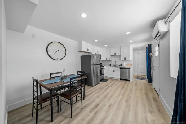 a kitchen with stainless steel appliances a refrigerator a oven a sink dishwasher and a dining table with wooden floor