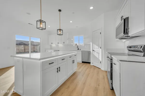 a large white kitchen with stainless steel appliances sink and cabinets