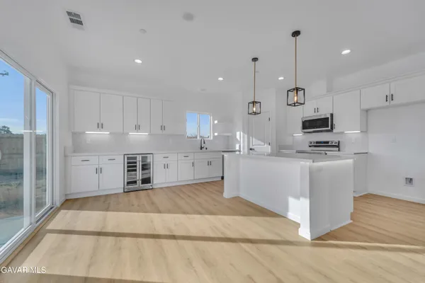 a large kitchen with stainless steel appliances kitchen island granite countertop a stove a sink a refrigerator and white cabinets