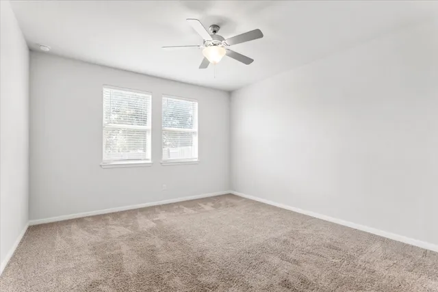 an empty room with windows and ceiling fan