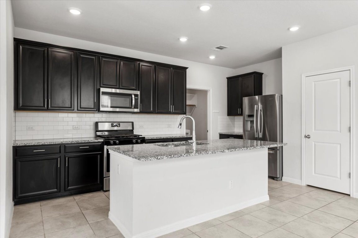 105 Otella Street Georgetown, TX 78628 - Photo 5 of 31 a kitchen with stainless steel appliances granite countertop a sink and a stove
