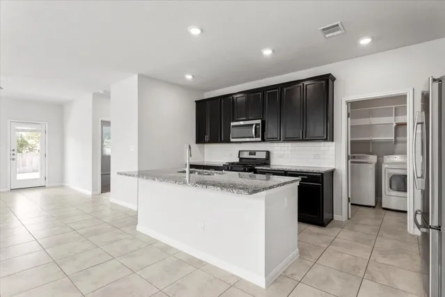 a kitchen with stainless steel appliances granite countertop a stove top oven a sink a counter top space and cabinets