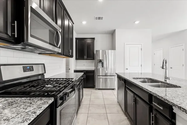 a kitchen with stainless steel appliances granite countertop a sink stove and refrigerator