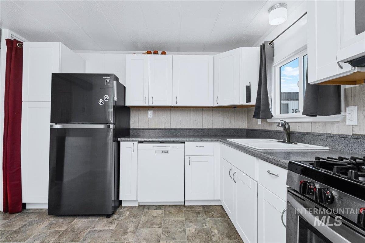 7701 West Ustick Road, Unit 14 Boise, ID 83704 - Photo 12 of 22 Kitchen featuring stainless steel appliances, dark countertops, stone finish flooring, and white cabinetry