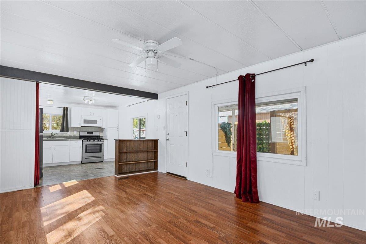 7701 West Ustick Road, Unit 14 Boise, ID 83704 - Photo 14 of 22 Unfurnished living room featuring plenty of natural light, a ceiling fan, dark wood-type flooring, and wood walls