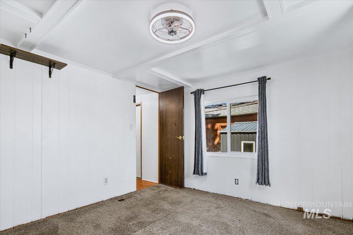 7701 West Ustick Road, Unit 14 Boise, ID 83704 - Photo 21 of 22 Spare room with wooden walls, carpet flooring, and beam ceiling