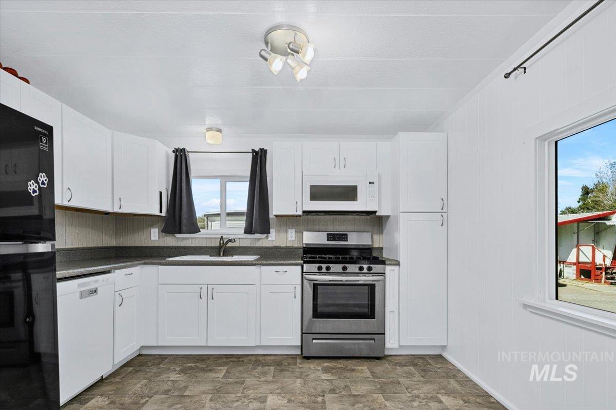 7701 West Ustick Road, Unit 14 Boise, ID 83704 - Photo 9 of 22 Kitchen featuring white appliances, white cabinetry, stone finish flooring, and wooden walls