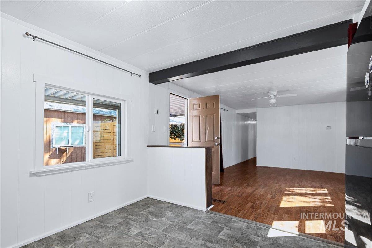 7701 West Ustick Road, Unit 14 Boise, ID 83704 - Photo 10 of 22 Unfurnished living room with beam ceiling, wood walls, stone finish flooring, and ceiling fan