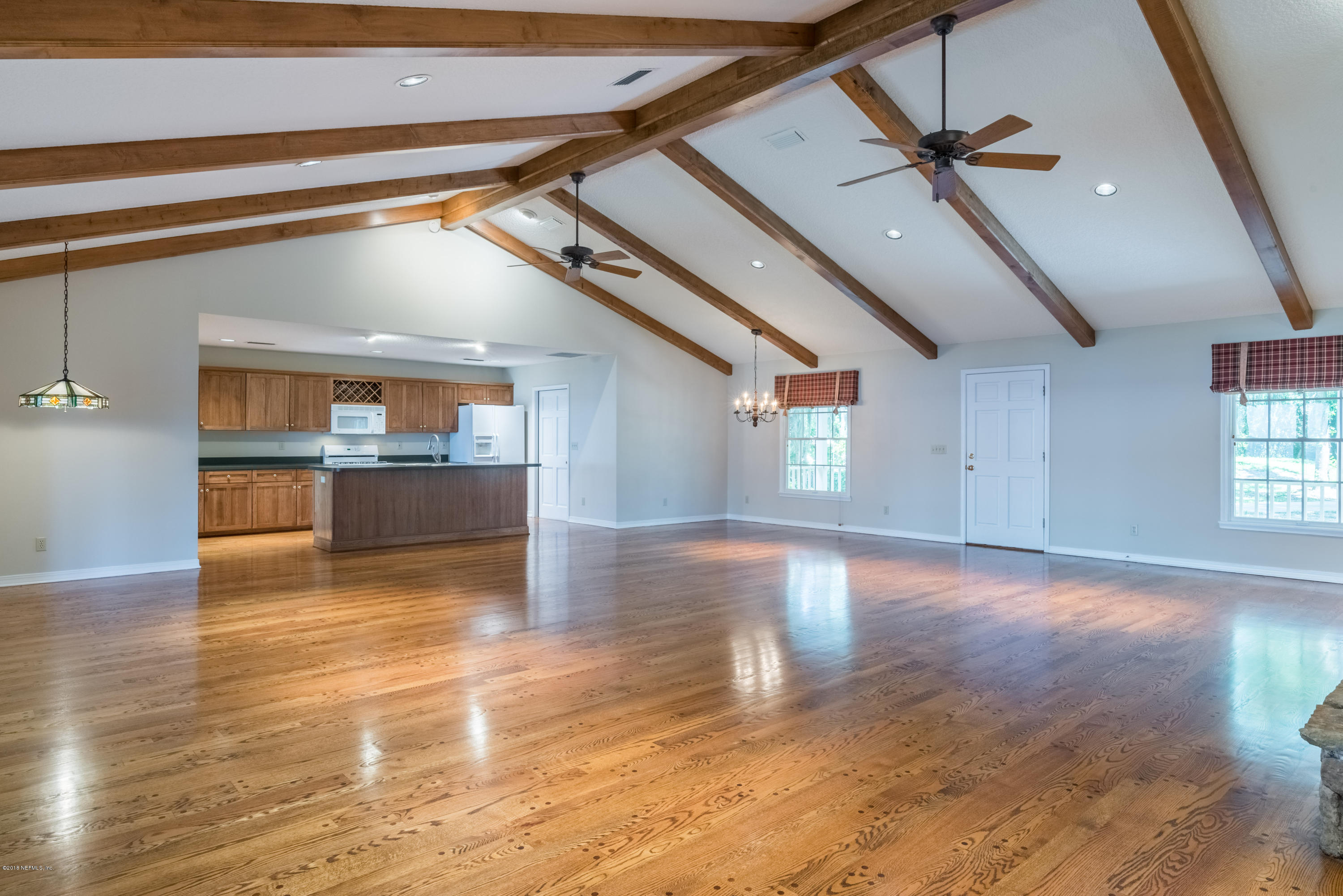 7867 Rusty Anchor Road St. Augustine, FL 32092 - Photo 17 of 36 a view of empty room with wooden floor and kitchen view